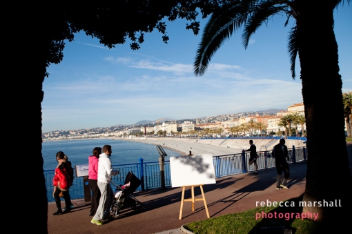 Pedestrians and joggers along Quai Rauba Capeu, a view of Nice seafront beyond