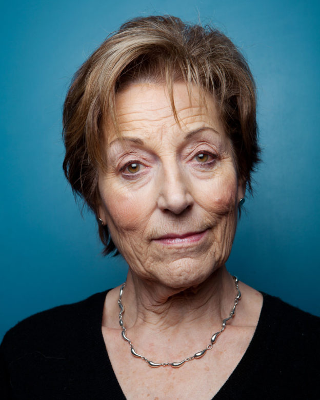 Headshot portrait of a senior woman on blue background
