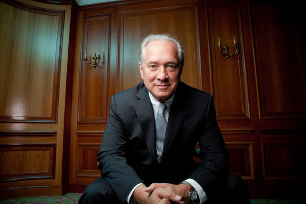 Portrait of a man in a wood-panelled room wearing a suit