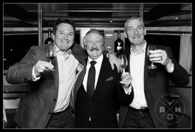 Three men post for a photograph, glasses of whisky in hand