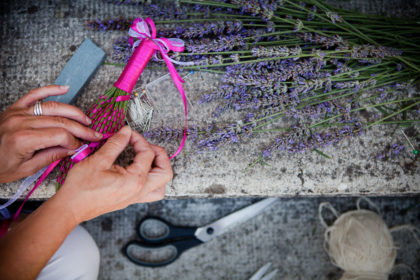 Photograph from overhead of a woman's hands making a lavender bottle