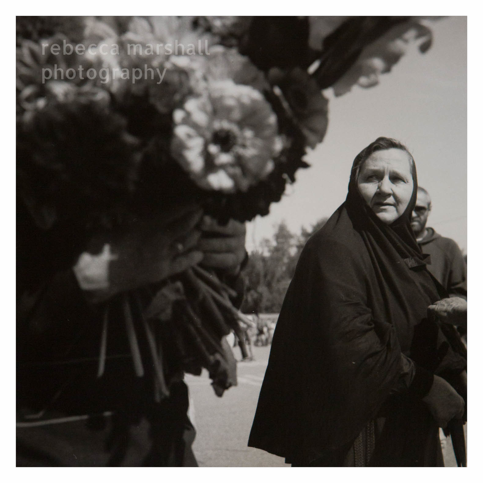 Black and white photograph of a nun looking at a bouquet of flowers