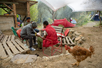 3 men of African origin play cards around a campfire in the daytime