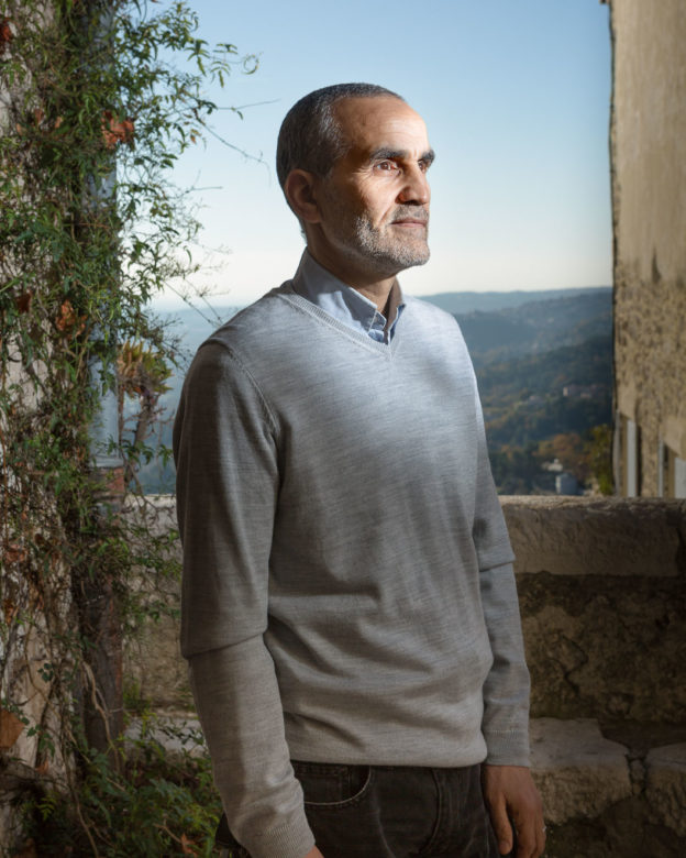 Portrait of a man standing by a village wall