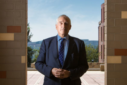 Man in suit poses for a portrait under blue sky