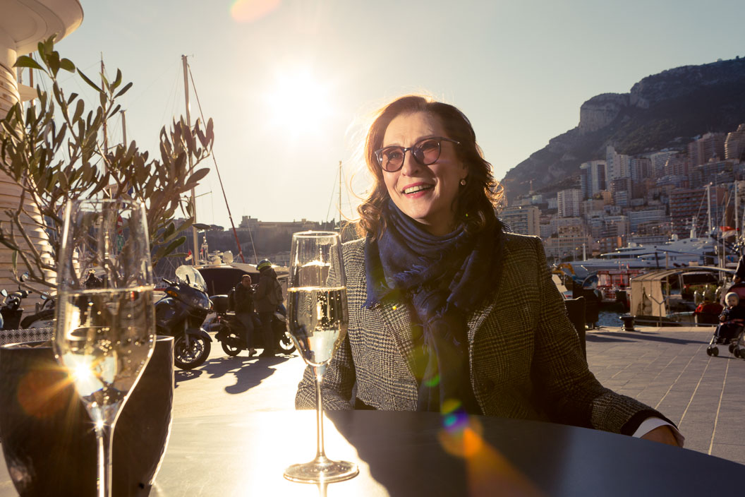 Woman sitting at a restaurant terrace in the sunshine, laughing