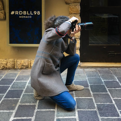 Photograph of photographer kneeling on pavement with camera
