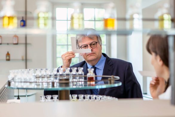 Man in a suit sniffs a perfume test strip in a laboratory