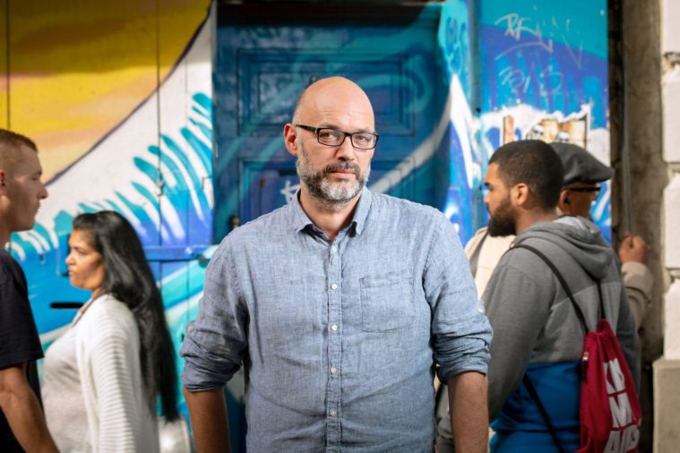 Portrait of a man in glasses standing still in a moving crowd