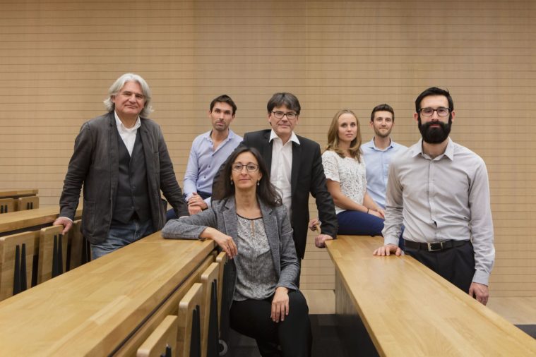 7 people pose for a group portrait in a wood-panelled room