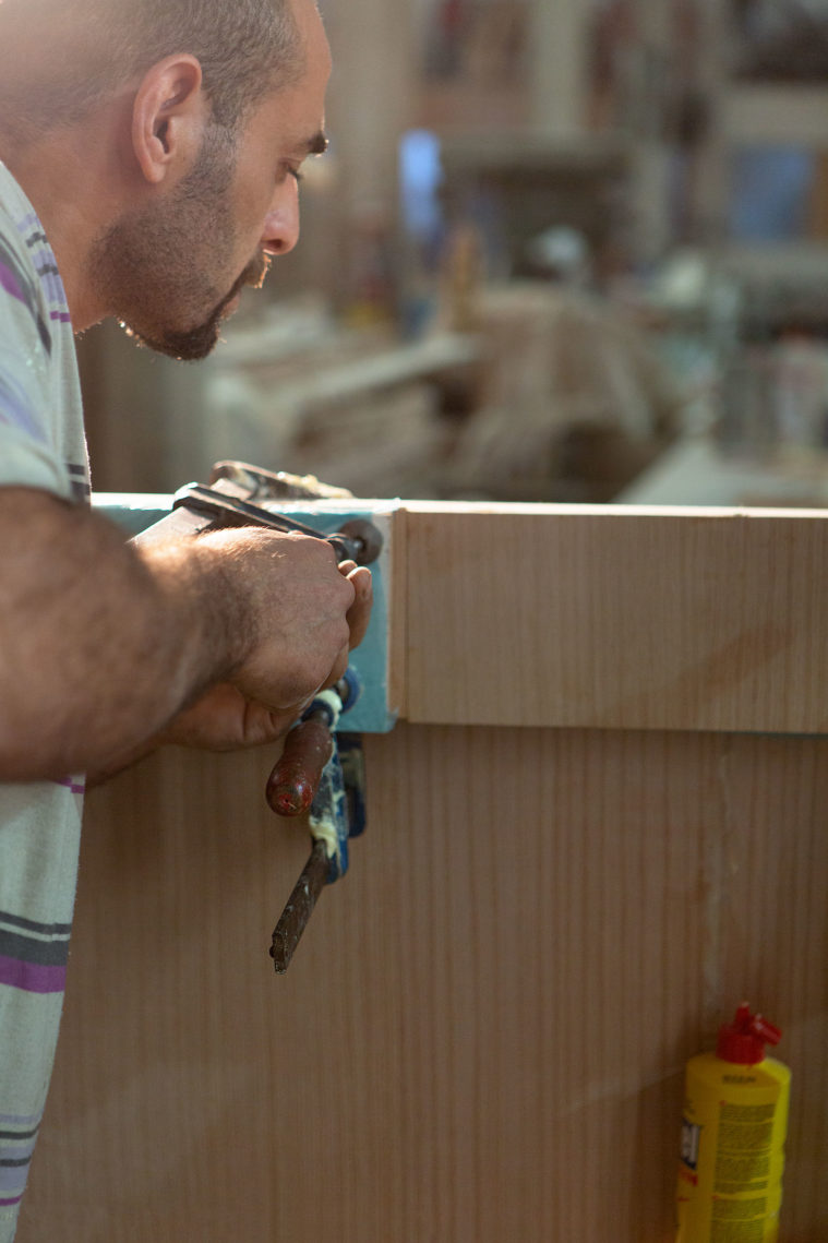 Close-up photo of a man tightening a clamp on a large piece of wood
