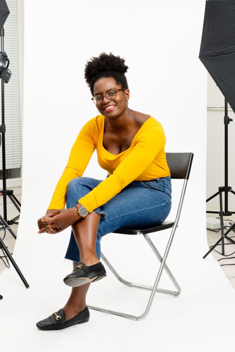 Black woman in yellow top poses for a studio photograph