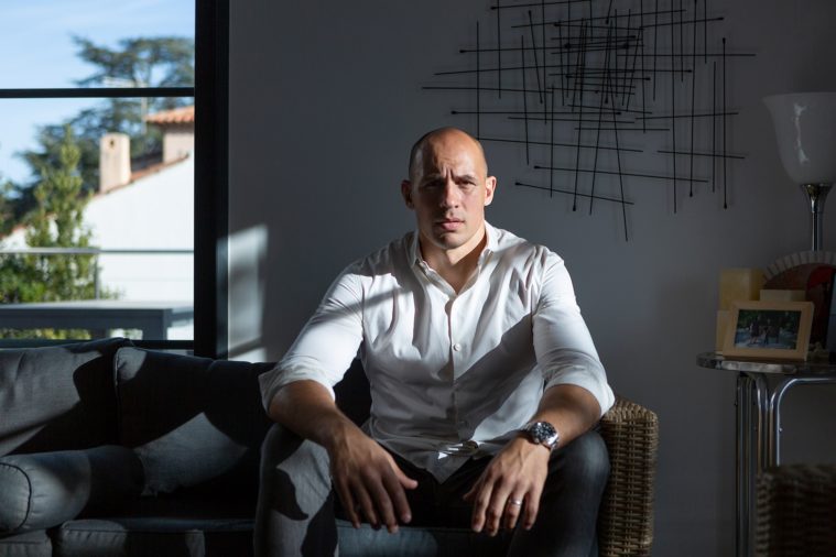 Man sitting on a couch in his home, facing the camera