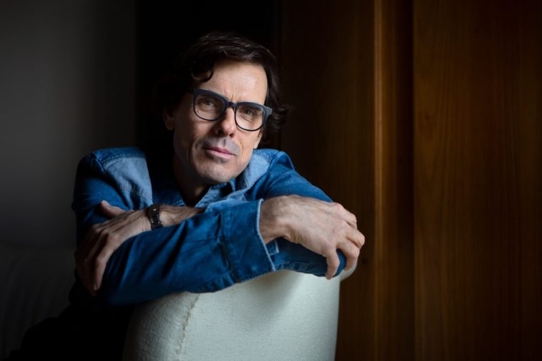 Portrait of a man in blue shirt leaning on armchair back