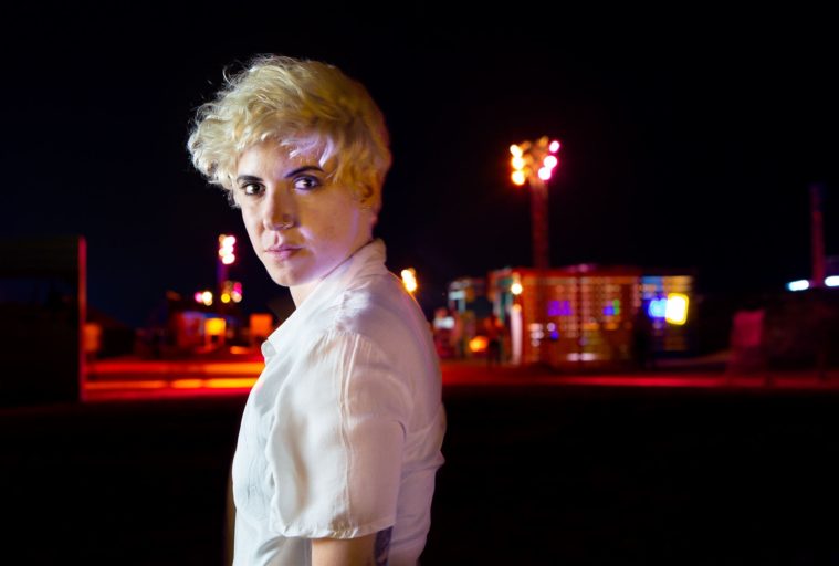 Portrait of woman in white shirt at night with coloured lights in background