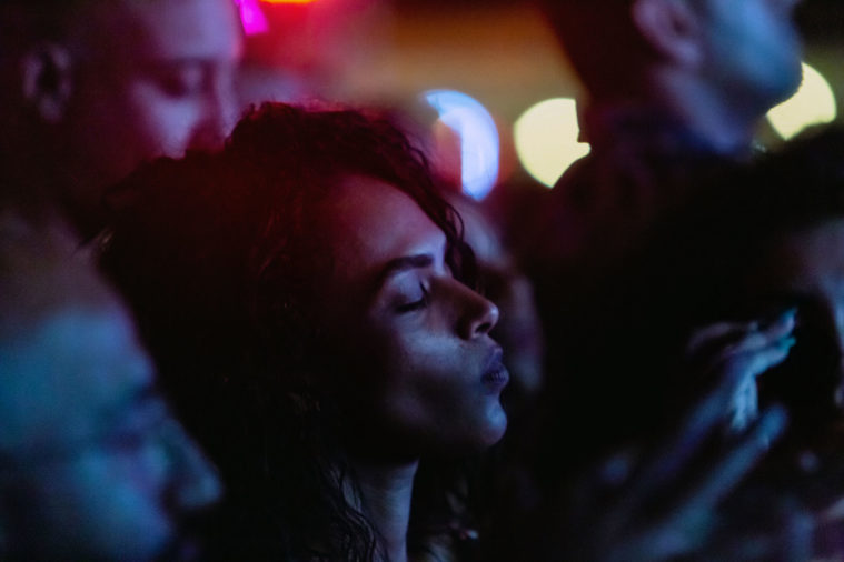 Photograph of a woman in a crowd at a festival at night, dancing with her eyes closed