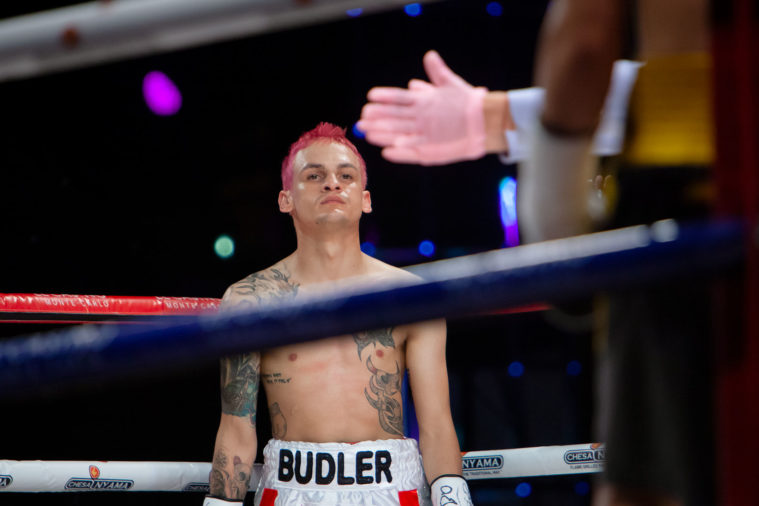 A boxer in the ring with the referee's pink gloved hand foreground