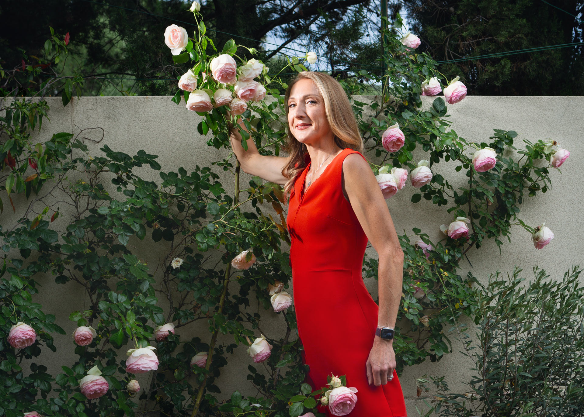 Portrait of a woman in a red dress smelling roses