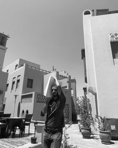 Black and white photograph of a man carrying cement slabs