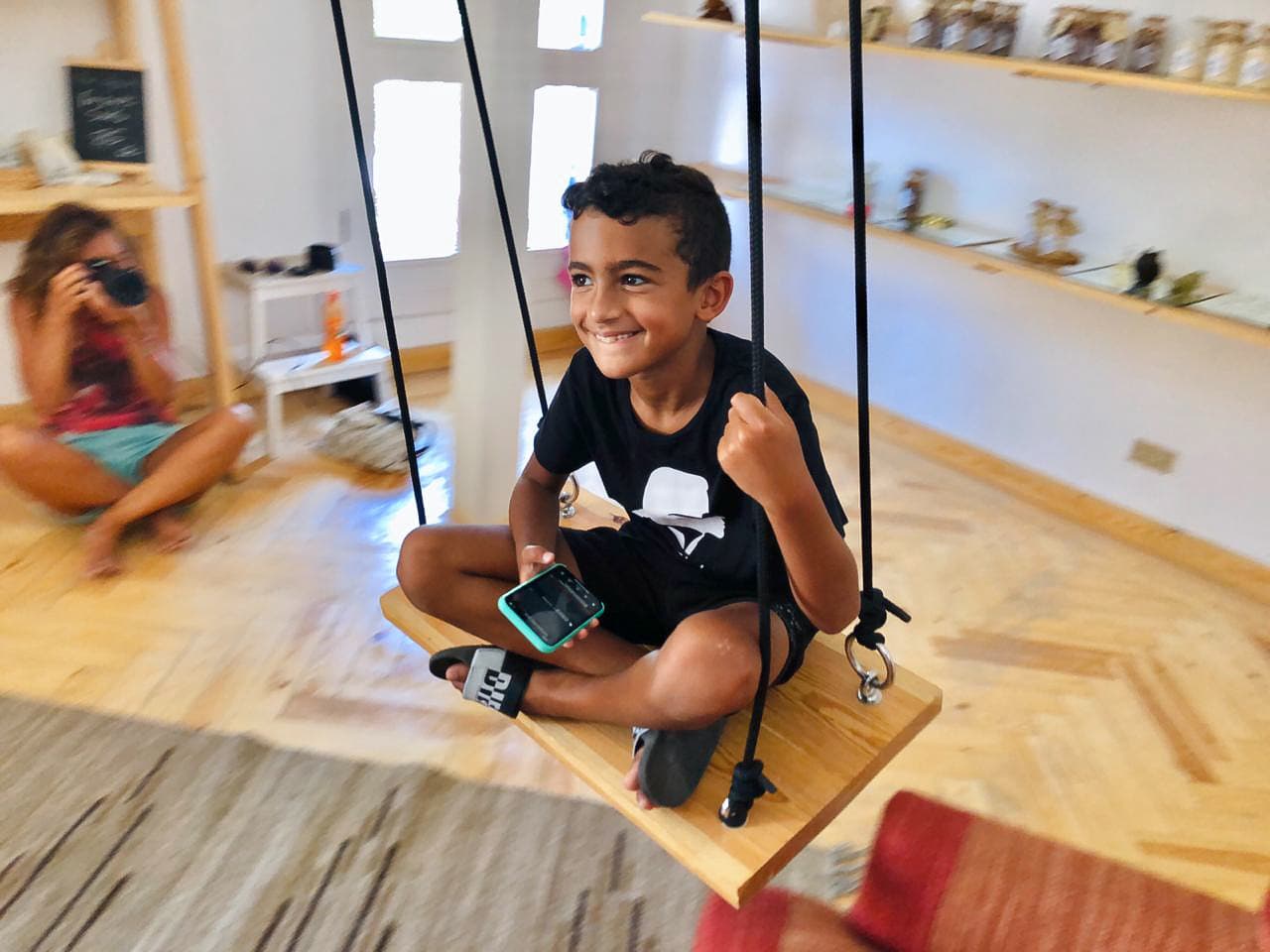 Photograph of a boy smiling on an indoor swing