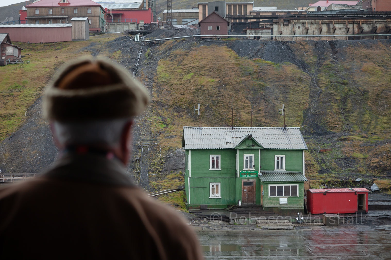 A man (viewed from the back) looks out at a coal mining town