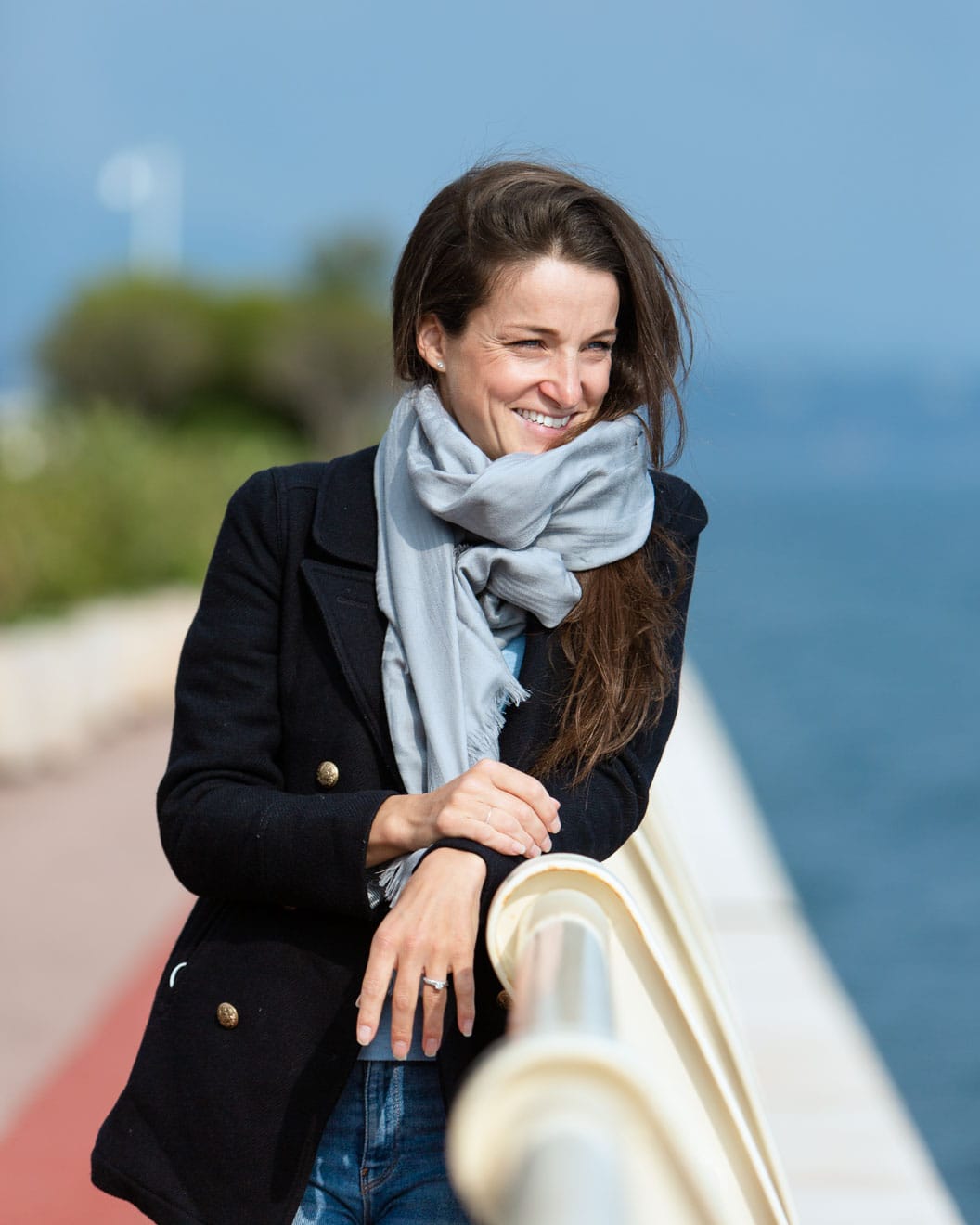 Photographic portrait of Lizzie Deignan leaning on a railing, looking out to sea and smiling