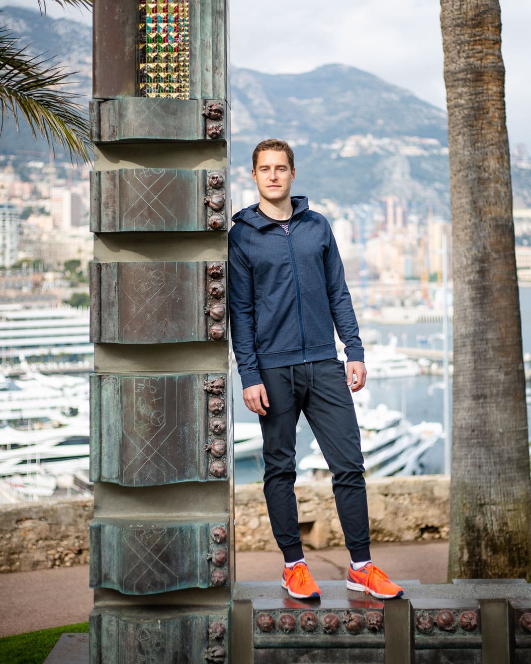 Portrait of man in sportswear standing on a monument overlooking Monaco harbour