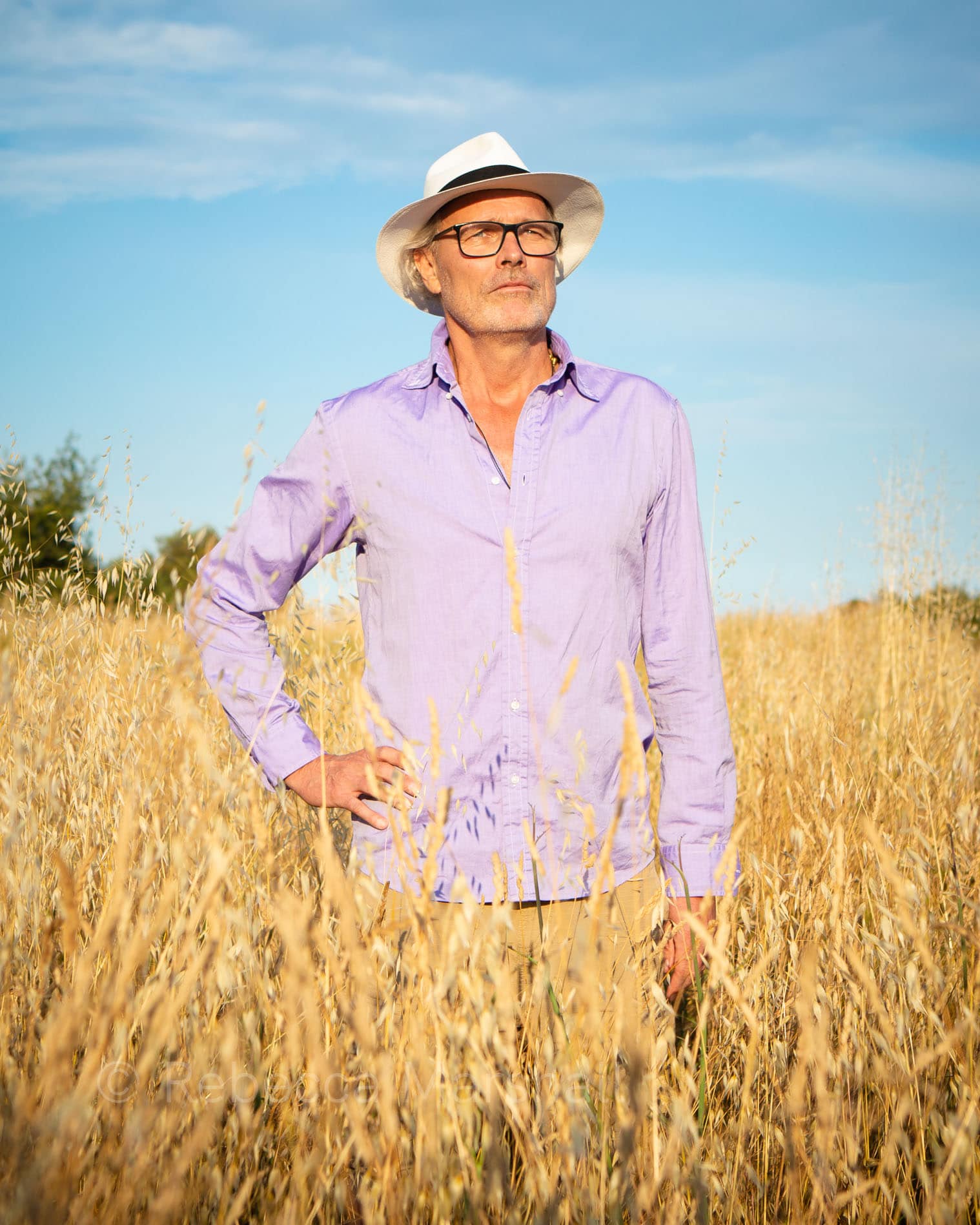 Photographic portrait of a man standing in a cornfield in a white hat
