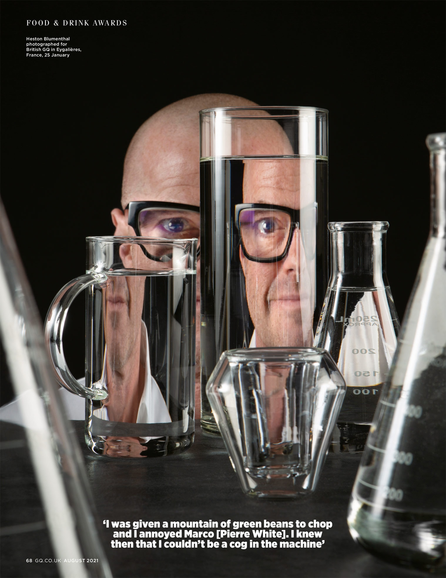 Page from magazine showing a studio photograph of Heston Blumenthal against a black background looking through glass containers