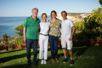 Two women and two men pose for the photographer on a lawn overlooking the sea