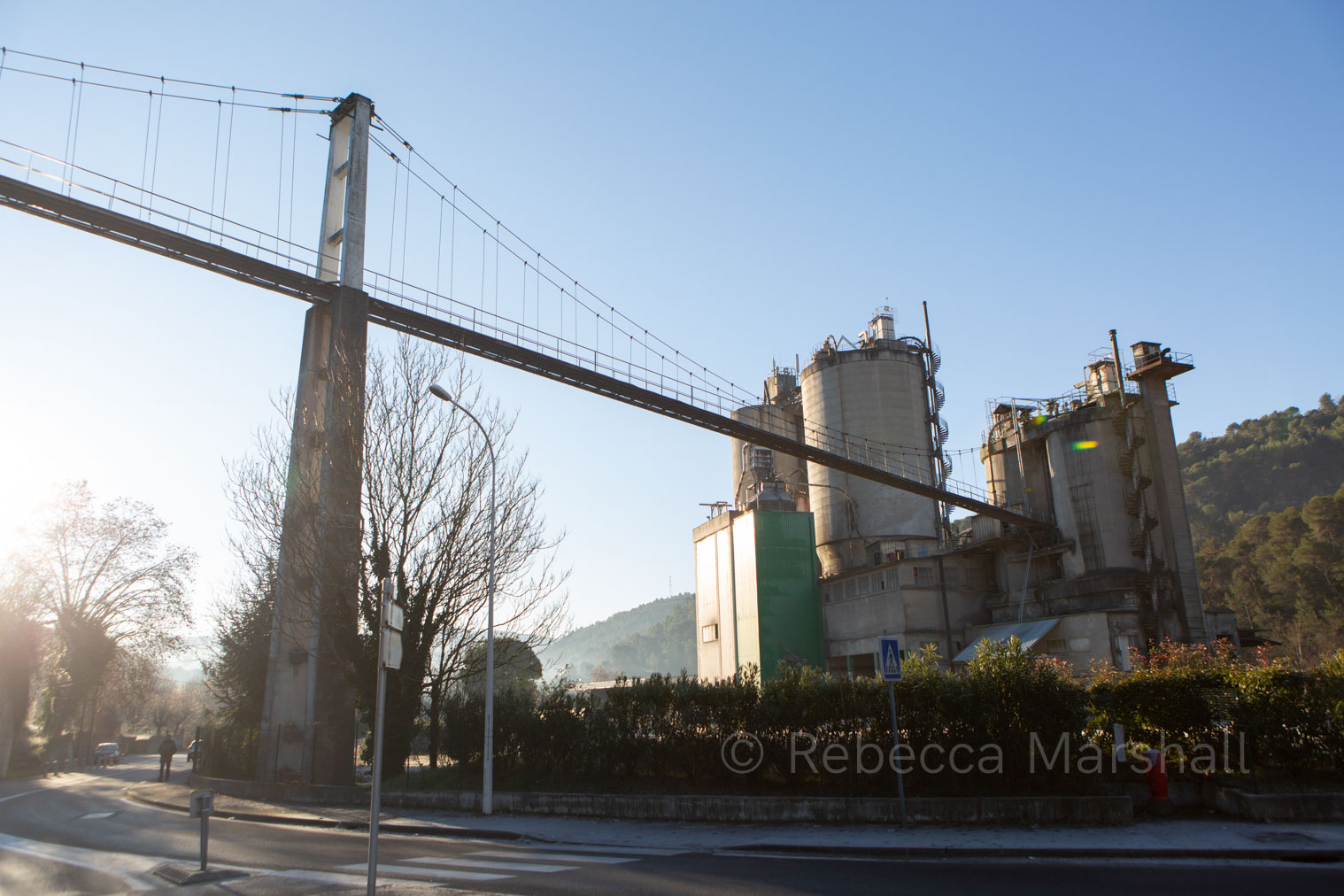 Photograph of the towers of a cement factory beside a road