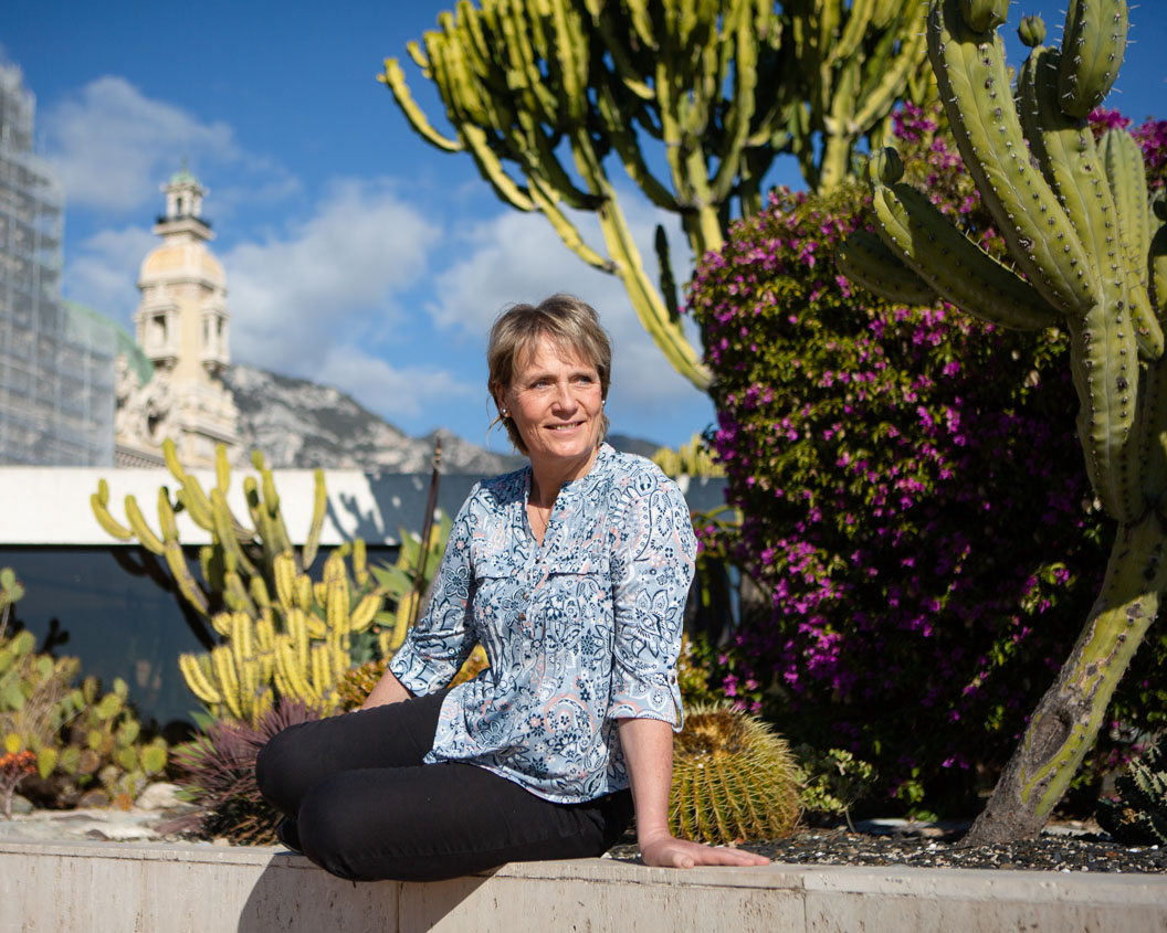 Woman sitting on a wall in a park with cacti in the background