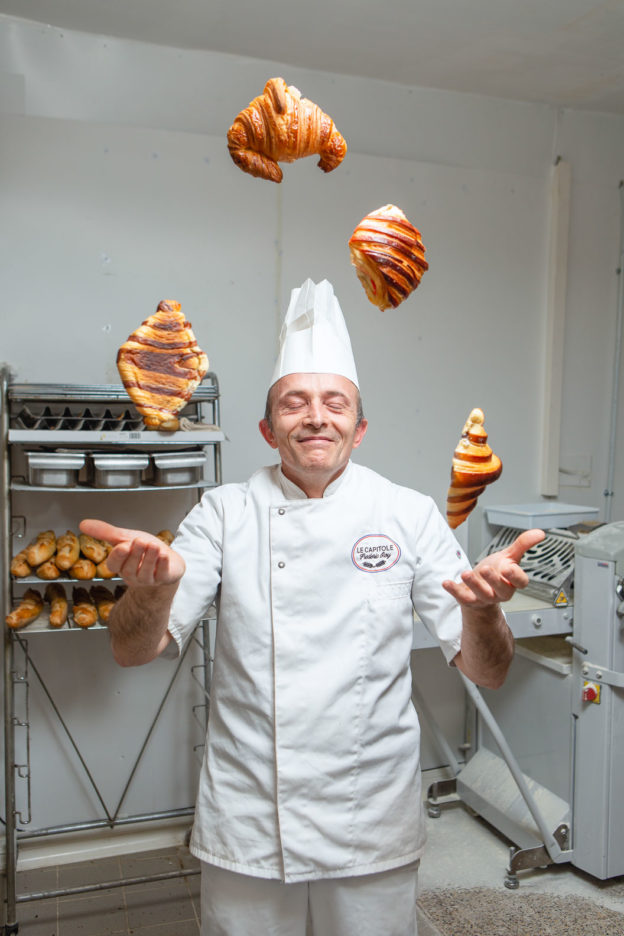 Portrait of a baker with his eyes closed, juggling 4 croissants