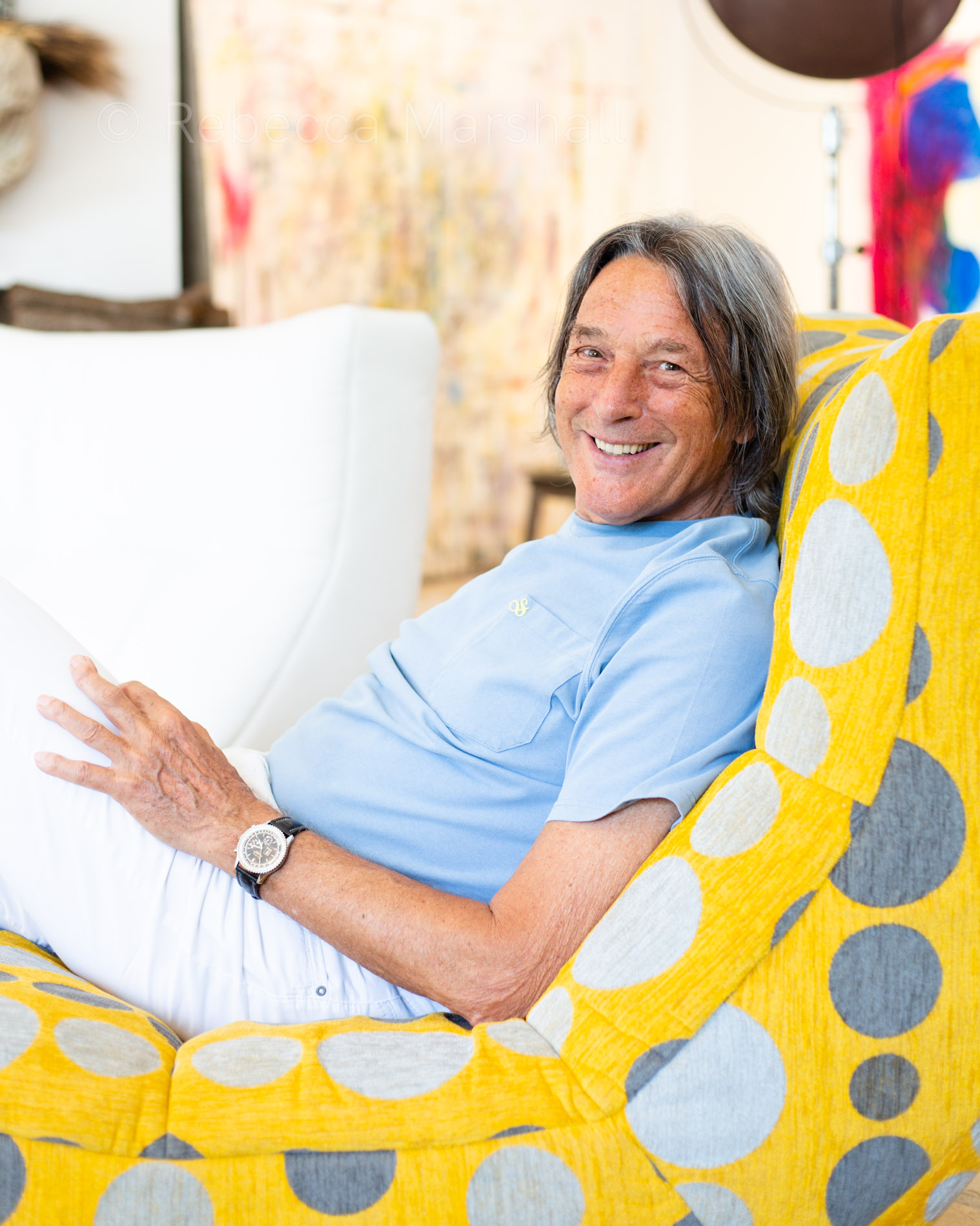 Smiling man in blue t-shirt sitting on a yellow spotted couch