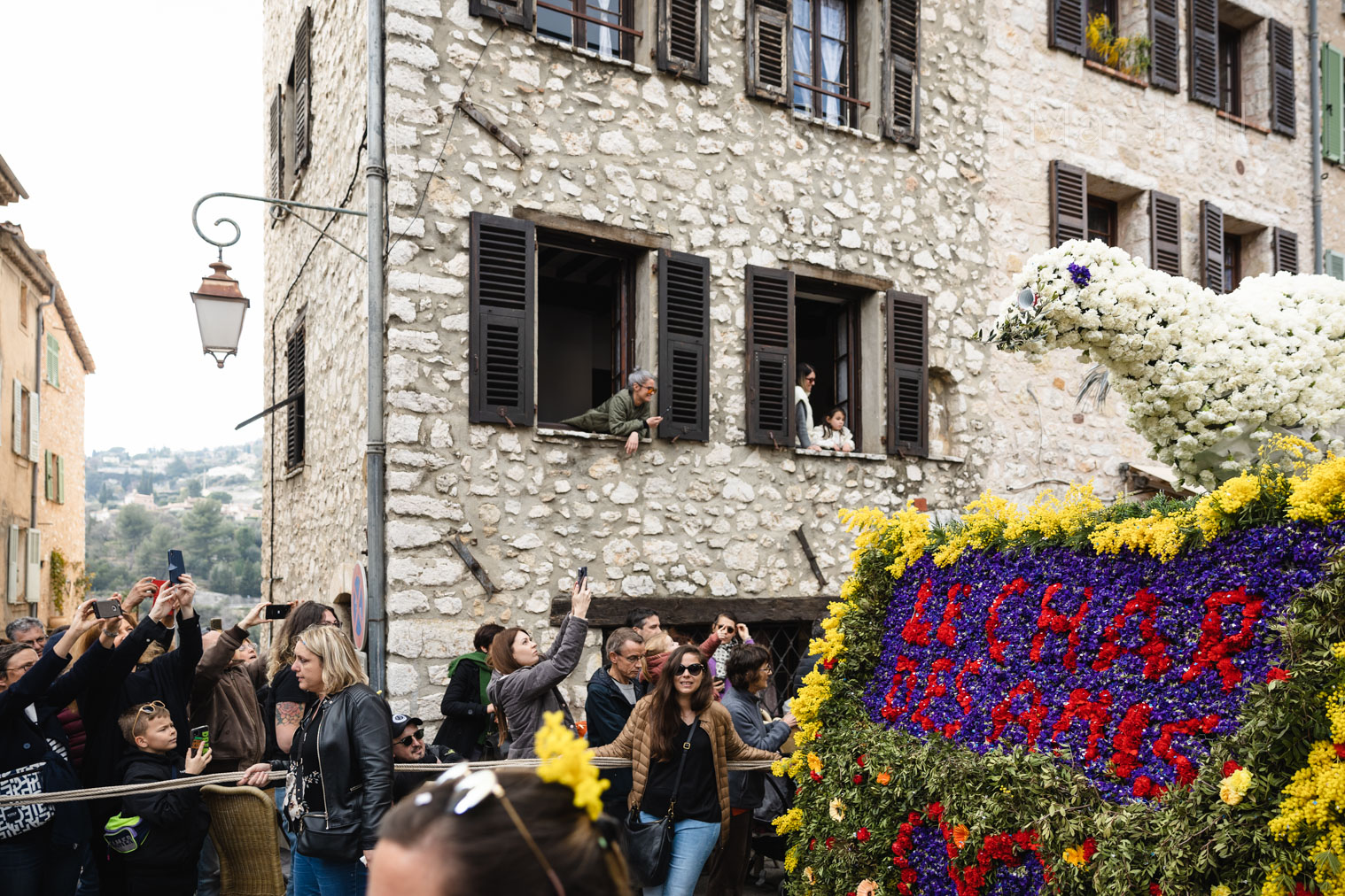 A float decorated with flowers passes by a village crowd