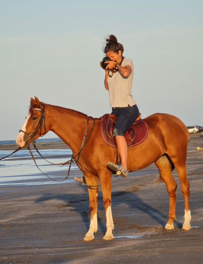 Photographer Rebecca Marshall sits on back of horse taking picture