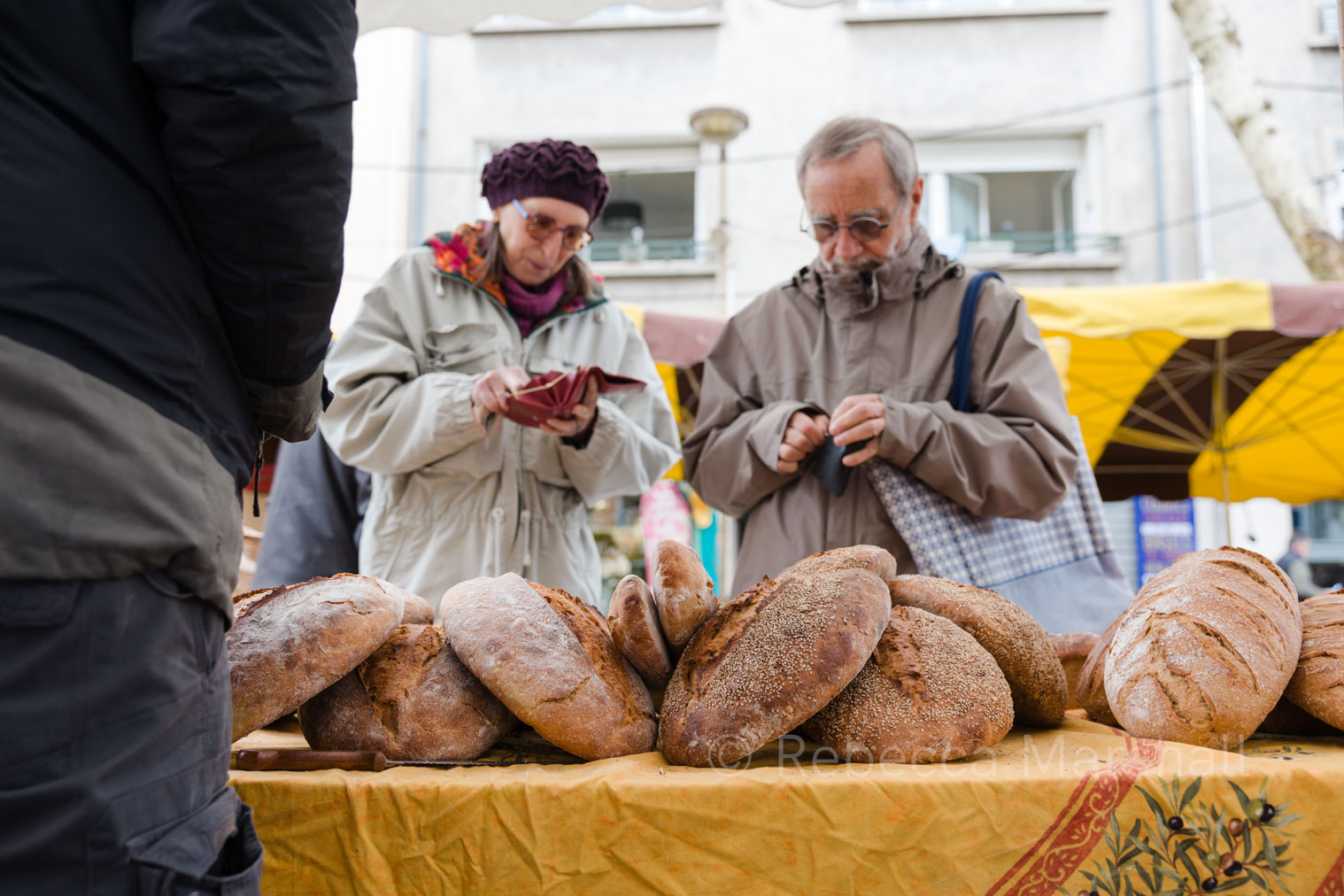 Buying Bread Photograph of a couple, looking for money in their purses at a bakery stall at a market