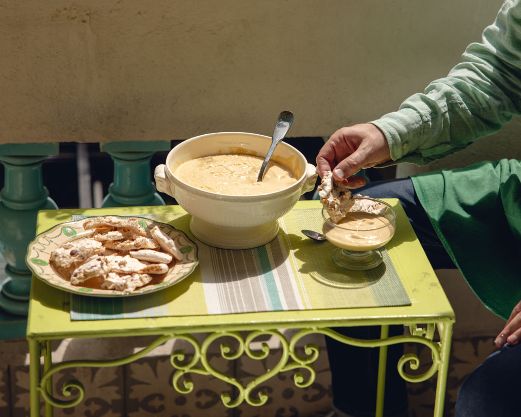Close-up photograph of the hands of a chef preparing Crema al Moscatello, a whispy cream, flavoured with sweet wine, served with meringue and hazelnut biscuits