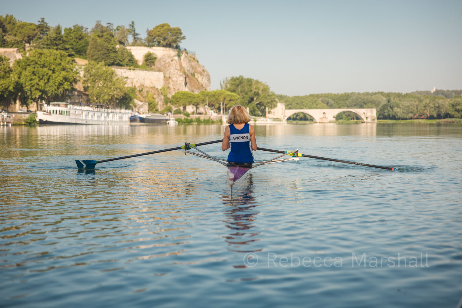 Rowing on the Rhône Photograph of Pauline Fry's back as she rows down the Rhône river, the Pont d'Avignon in the distance